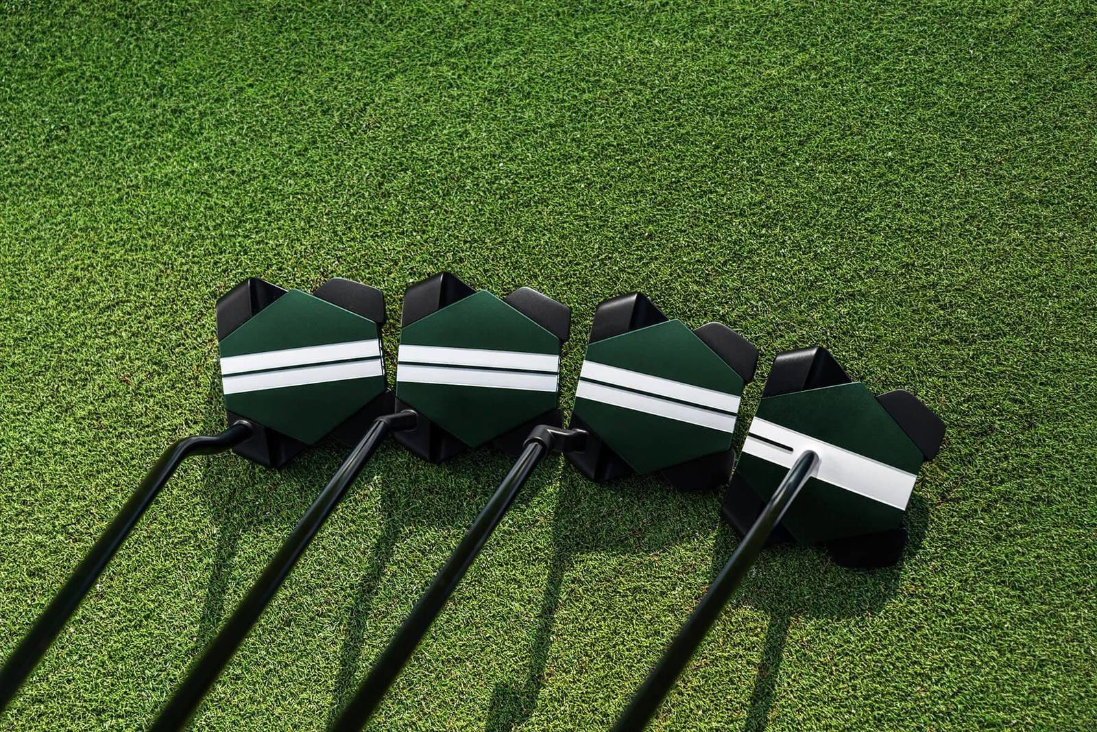 The four Odyssey TRTL putters lined up on the grass: DB, S, CH and Max